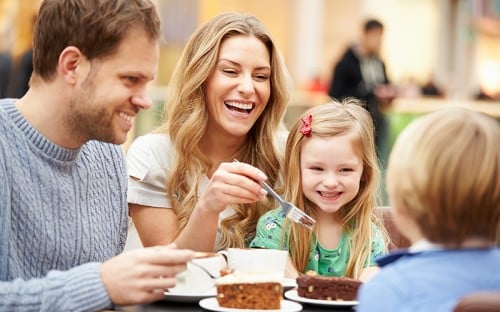 A man, woman, and young child laughing and eating pastries