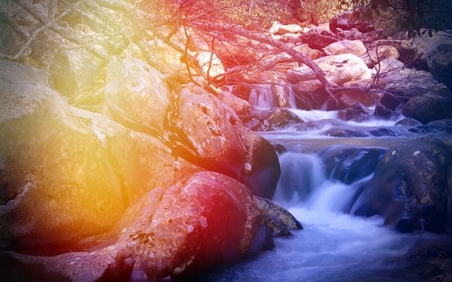 An illustration of water streaming down rocks with trees
