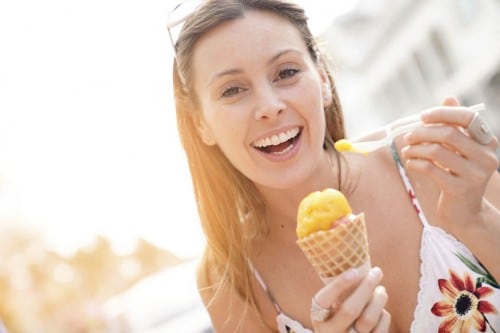 Young woman smiling eating a cone of ice cream with a spoon